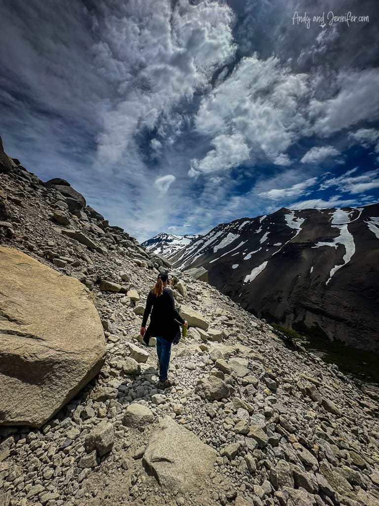Hikers trekking across a rocky mountain path under dramatic clouds