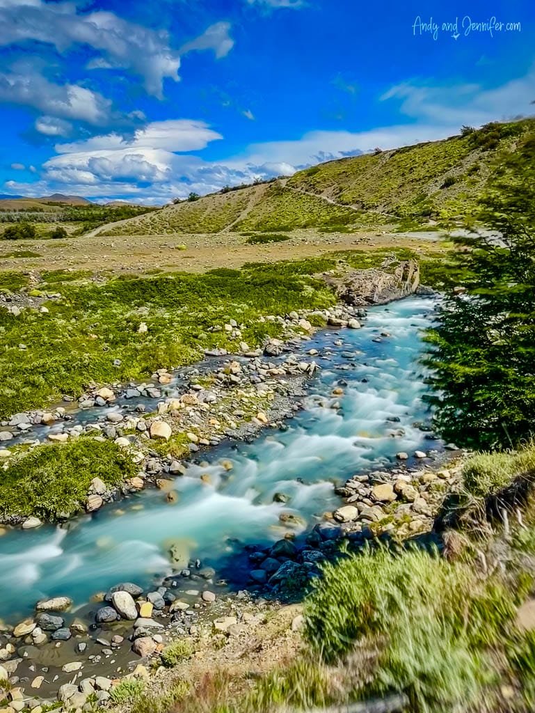 Flowing river through lush green valley under blue sky