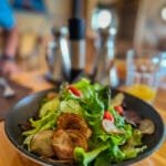 Fresh salad with mixed greens, cherry tomatoes, and crispy potatoes