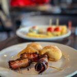 Plate of bacon-wrapped dates with other pastries in soft focus