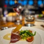 Gourmet salad with prosciutto-wrapped breadstick, asparagus, and cherry tomatoes.