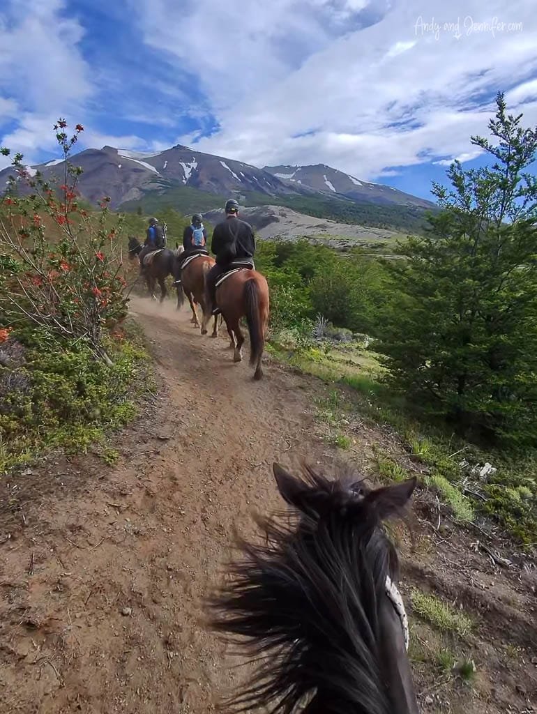 Horseback riders on a scenic dirt trail through mountains