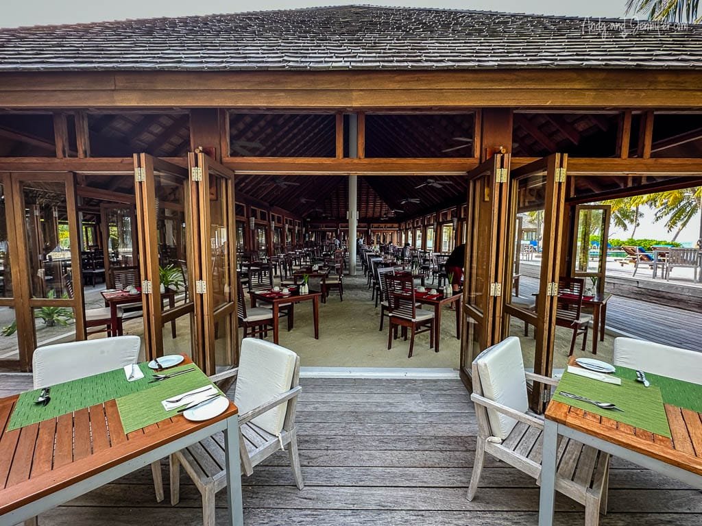 Open-air restaurant with wooden tables and green placemats.