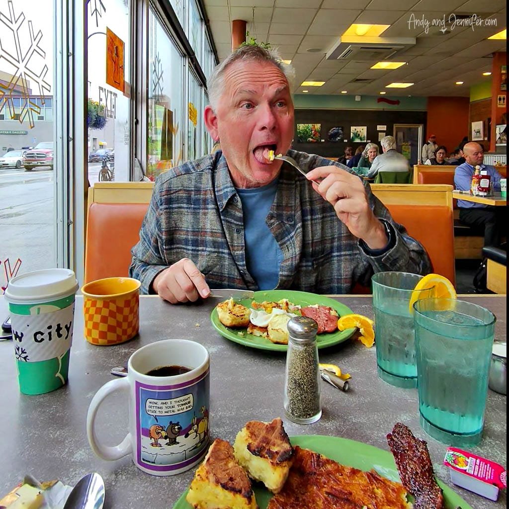 Man enjoying breakfast at a diner with coffee and plates of food