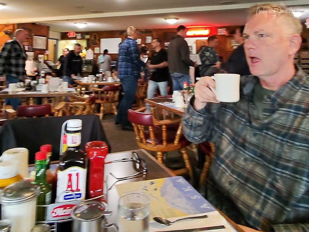 Man drinking coffee in a busy, rustic diner