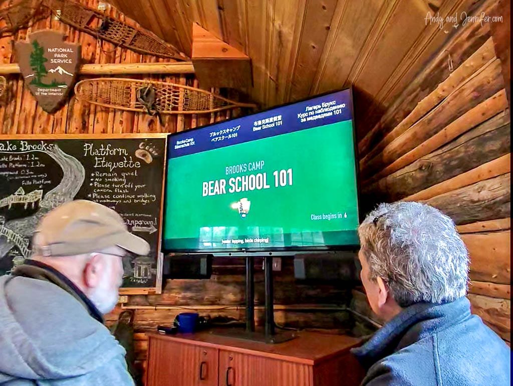 Visitors watching 'Bear School 101' video in a log cabin