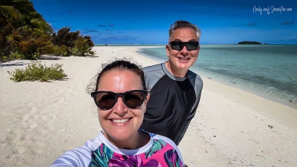 A couple enjoying the pristine white sand and turquoise lagoon on Aitutaki's picturesque beach.
