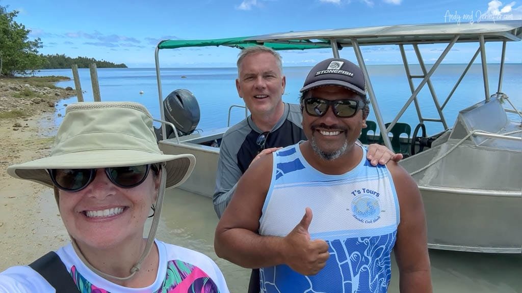 A couple posing with their guide from T’s Tours in front of a boat on Aitutaki’s lagoon.