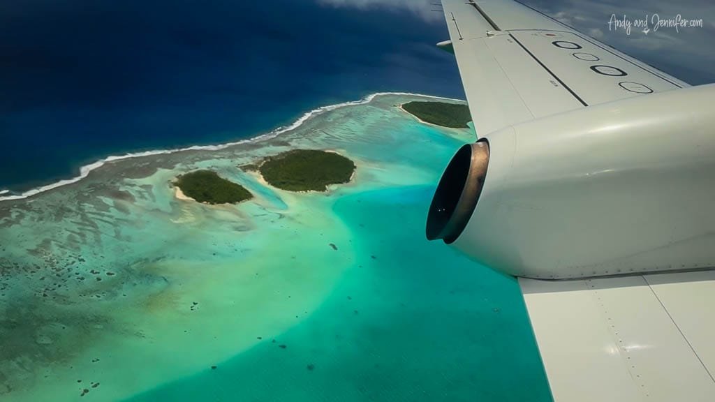  A stunning aerial view of Aitutaki's turquoise lagoon and motus, framed by the airplane wing during departure.