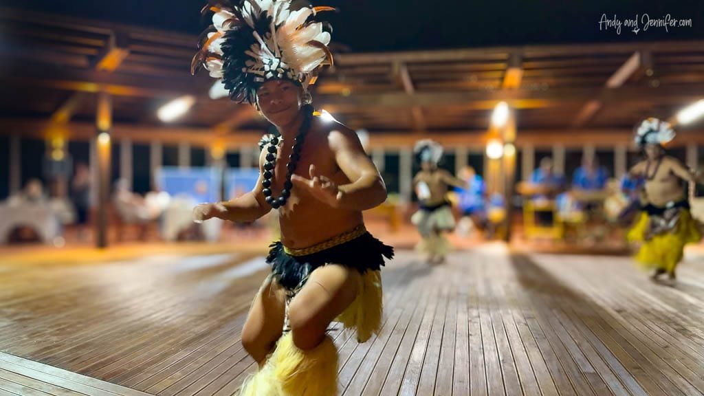 A Cook Islands cultural performer dressed in traditional attire dancing during a vibrant night show.