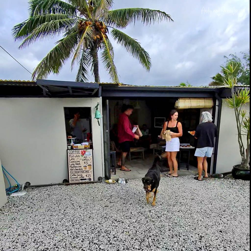 Small tropical coffee shop with palm tree, customers, and a dog.