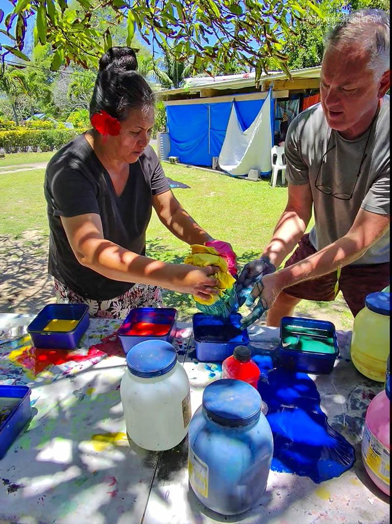 Experimenting with colorful dyes under the shade of a tree during a tie-dye workshop on Rarotonga.