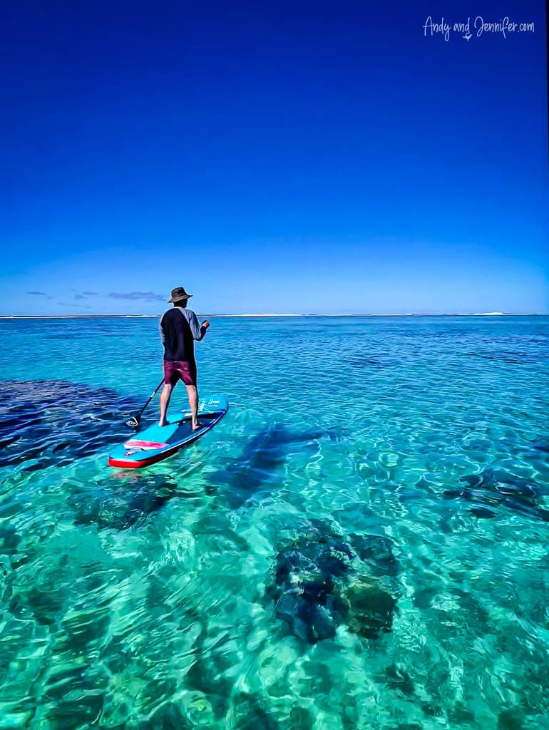Paddleboarding over crystal-clear waters in Aitutaki’s stunning lagoon, surrounded by endless blue skies.