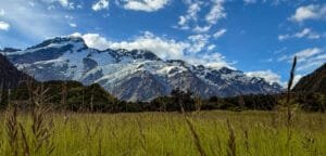 Snowy mountain peaks rising above green valley and grassy field