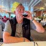 Man in paper crown sipping red wine