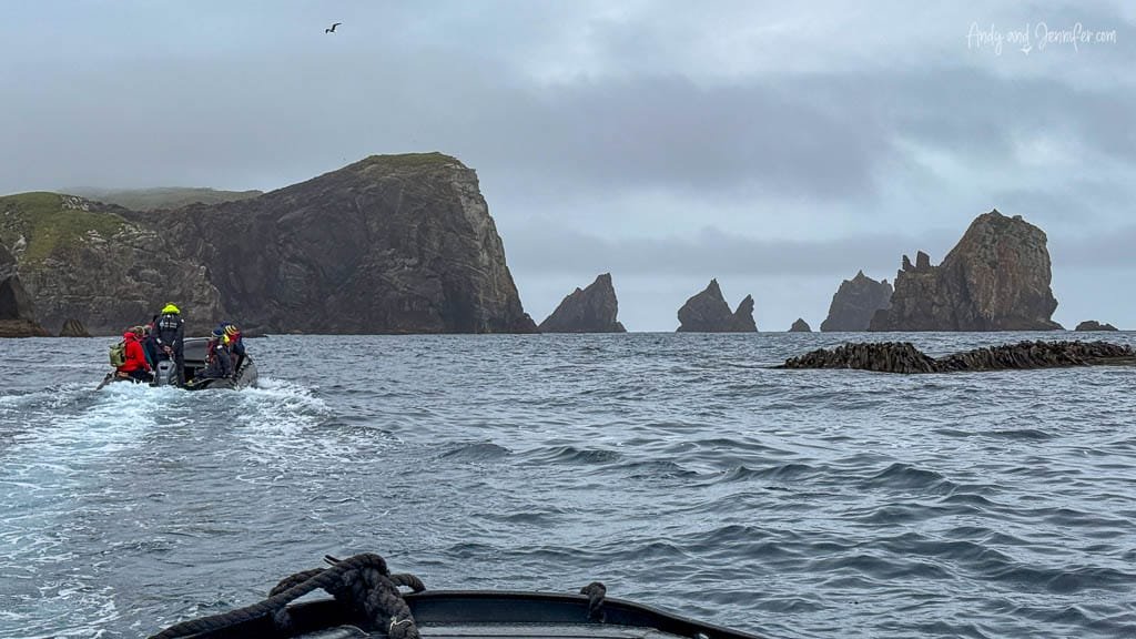 Zodiac boat approaching jagged sea stacks