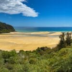 Golden sandy tidal flats surrounded by lush green hills