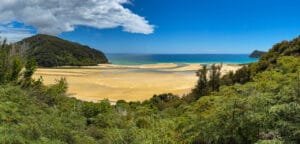Golden sandy tidal flats surrounded by lush green hills