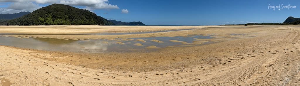 Wide sandy estuary at low tide under blue sky