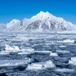 Snowy Arctic mountains behind sea ice and glacier