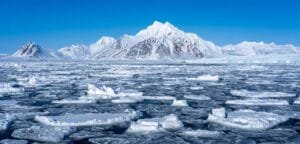 Snowy Arctic mountains behind sea ice and glacier