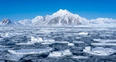 Snowy Arctic mountains behind sea ice and glacier