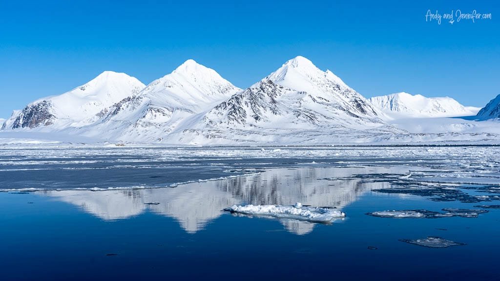 Snowy mountains reflected in calm Arctic water