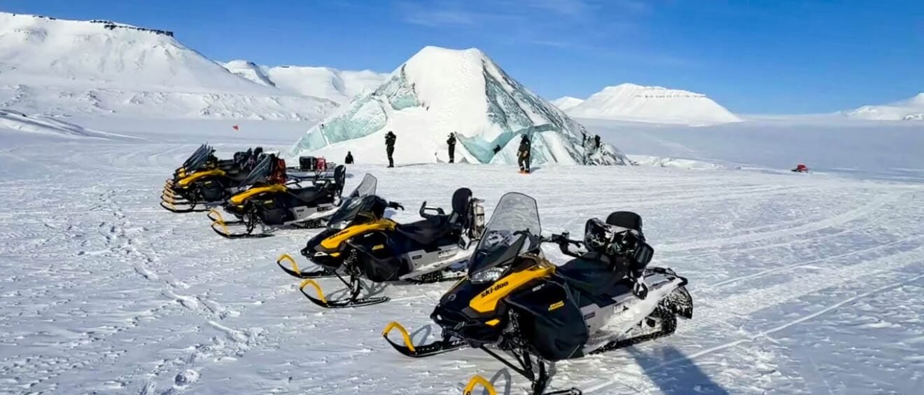 Snowmobiles parked near Arctic ice cave formation