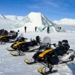 Snowmobiles parked near Arctic ice cave formation