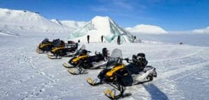 Snowmobiles parked near Arctic ice cave formation