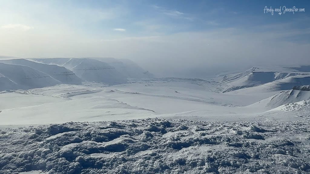Vast Arctic tundra with snowmobile tracks and mountains