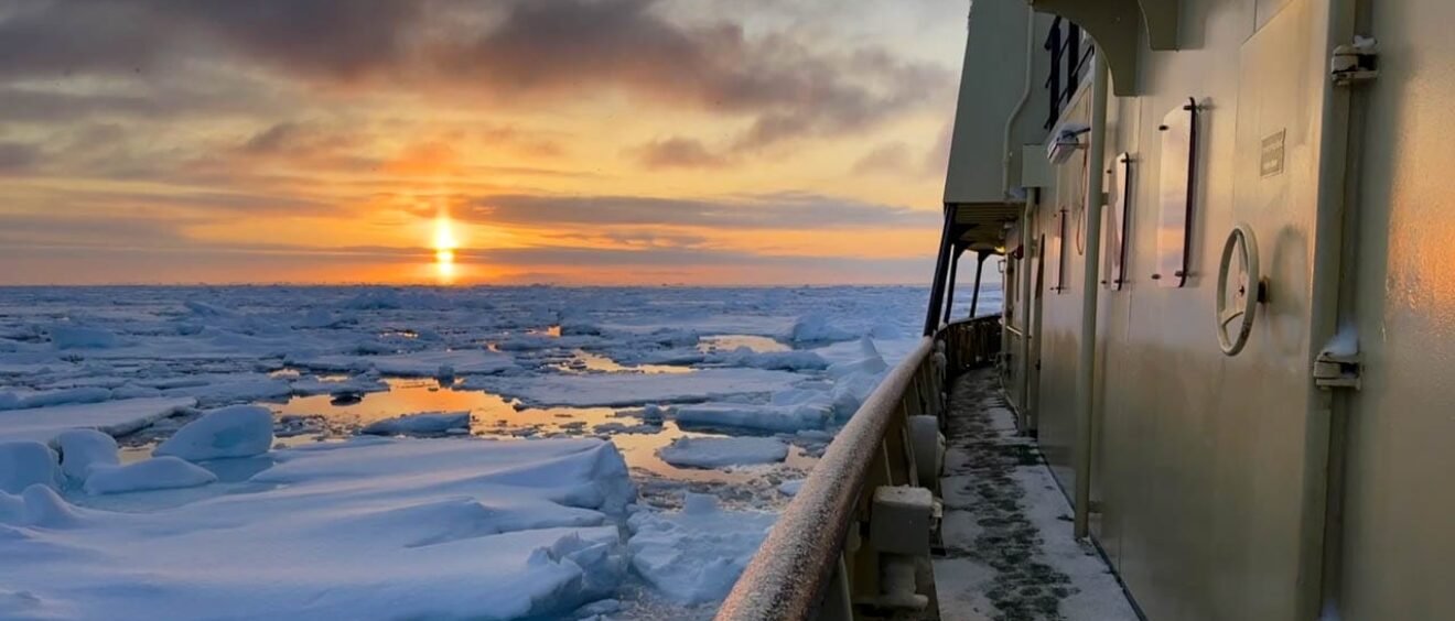 Arctic ice floes at sunset beside ship walkway
