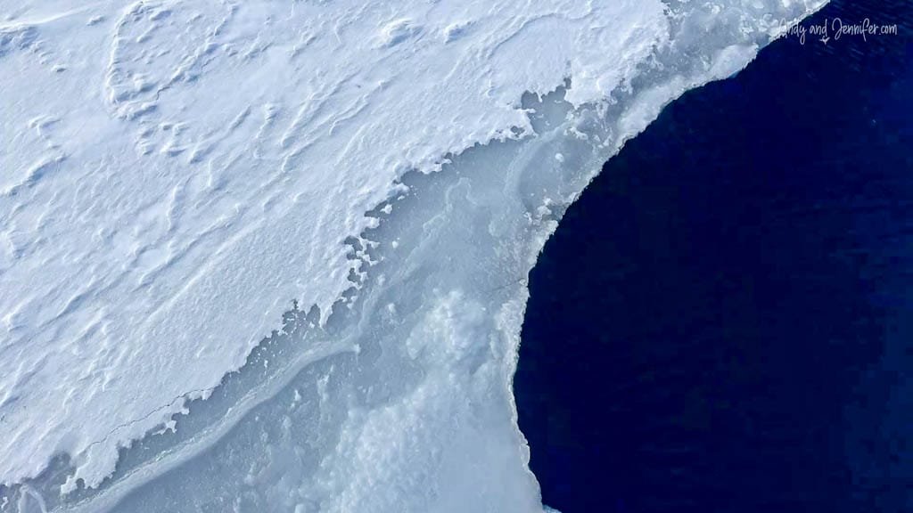 Curved ice shelf edge against dark Arctic ocean