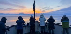 Passengers photographing Arctic sunrise from ship bow