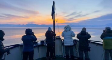 Passengers photographing Arctic sunrise from ship bow