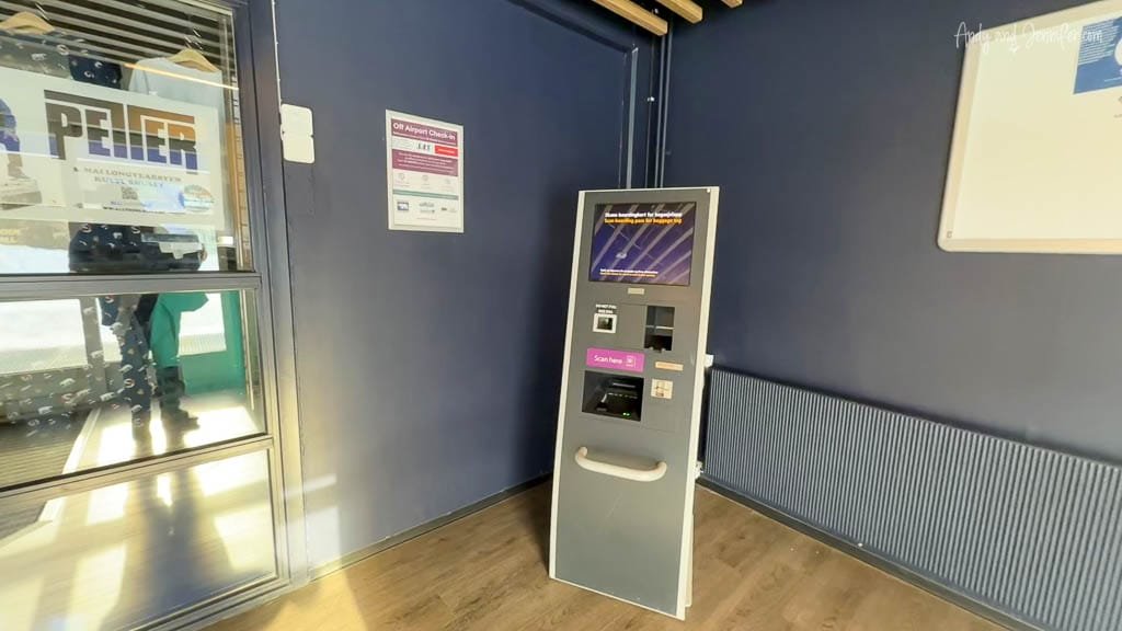 Self-service check-in kiosk at a terminal with signage on blue walls.