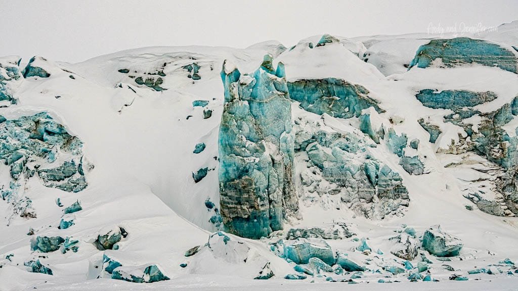 Towering blue ice cliff in snowy glacier wall