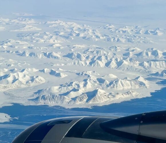 Aerial view of icy mountain range with jet engine.