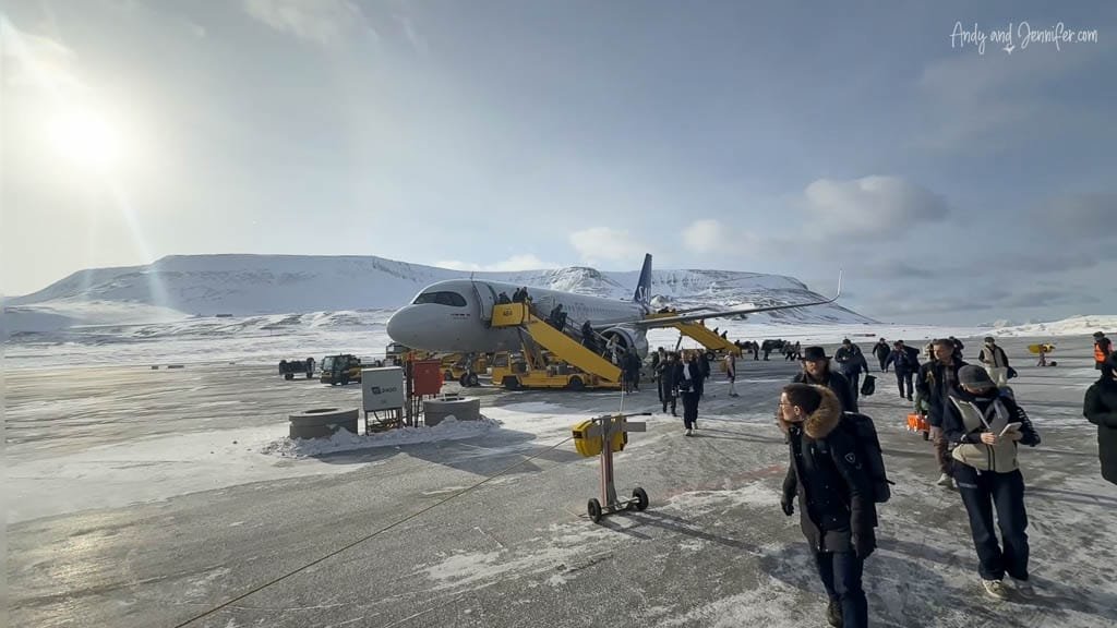 Passengers deboarding SAS plane in snowy arctic airfield.