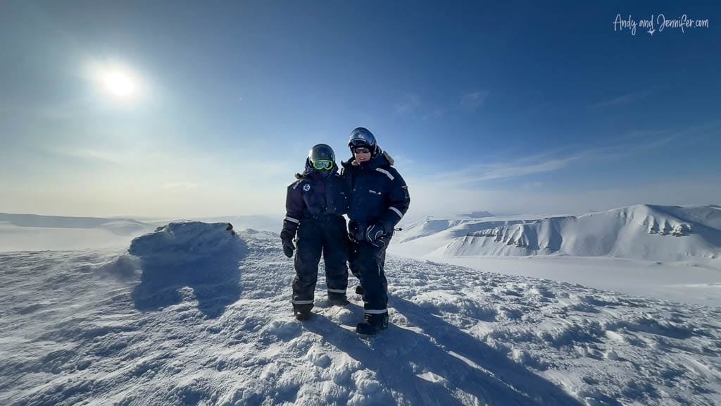 Two people in snowsuits on snowy Arctic ridge