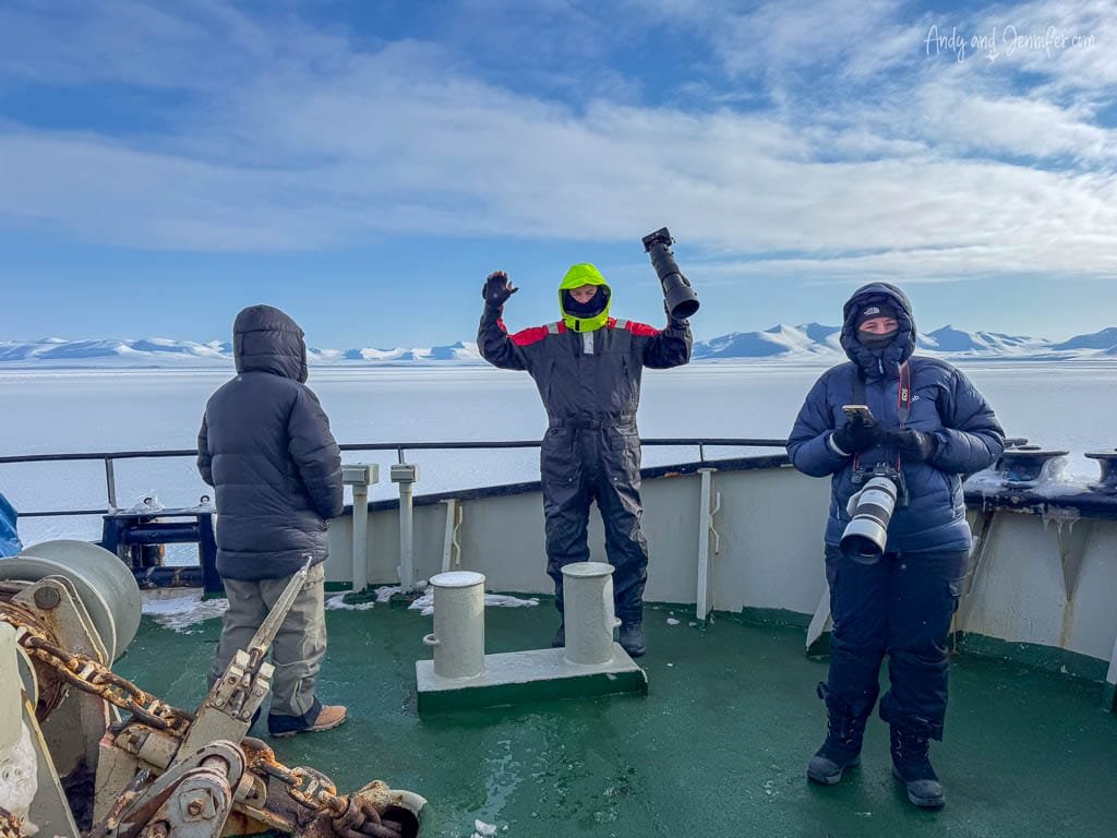 Photographers on ship deck in snowy Arctic fjord