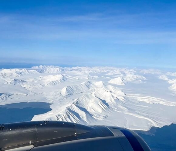 Snow-covered Arctic mountains seen from airplane window.