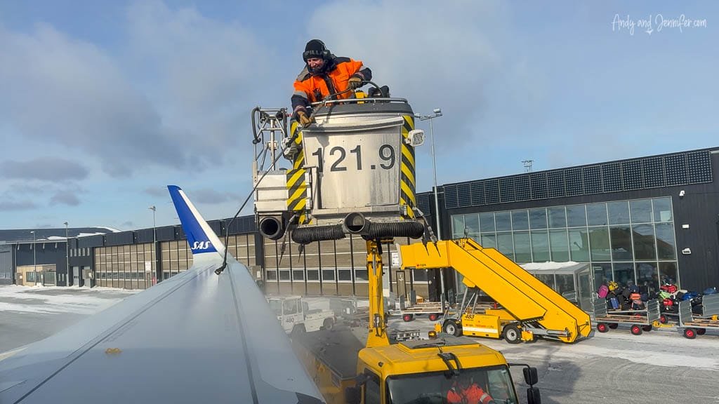 Ground crew deicing SAS airplane wing in winter weather.