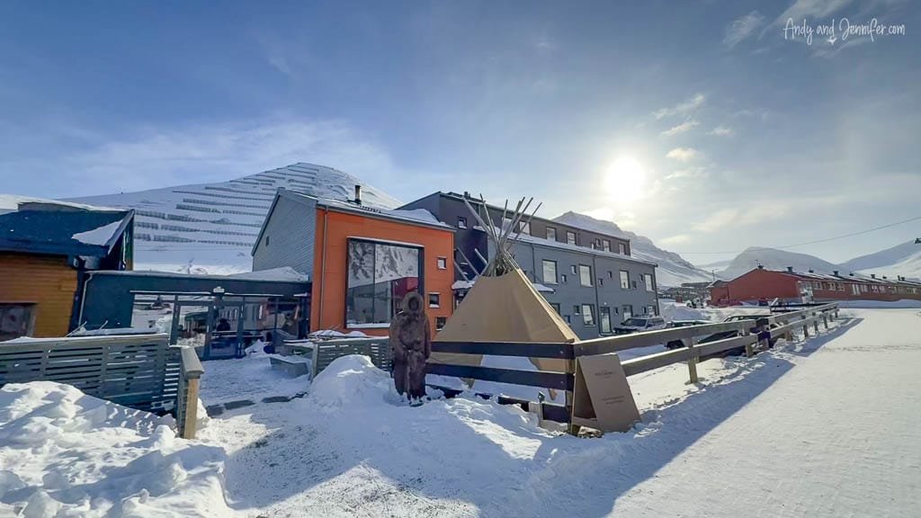Colorful Arctic buildings and lavvu (conical tent) in snowy sunlight