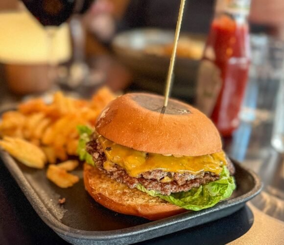 Cheeseburger with waffle fries served on black tray