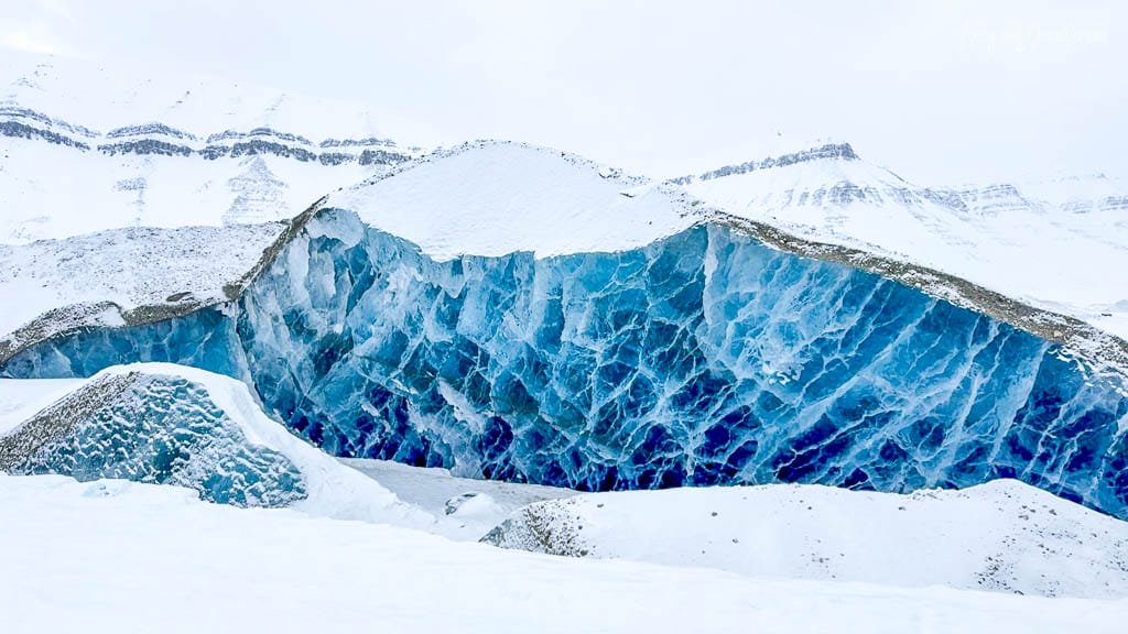 Vibrant blue ice cave in snowy Arctic landscape