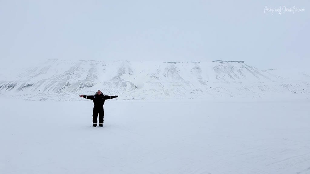 Person standing arms out in snowy Arctic plain