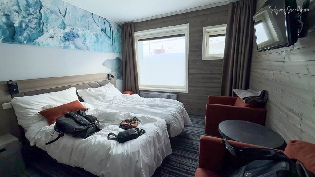 Cozy hotel room with twin beds, wood paneling, and travel bags