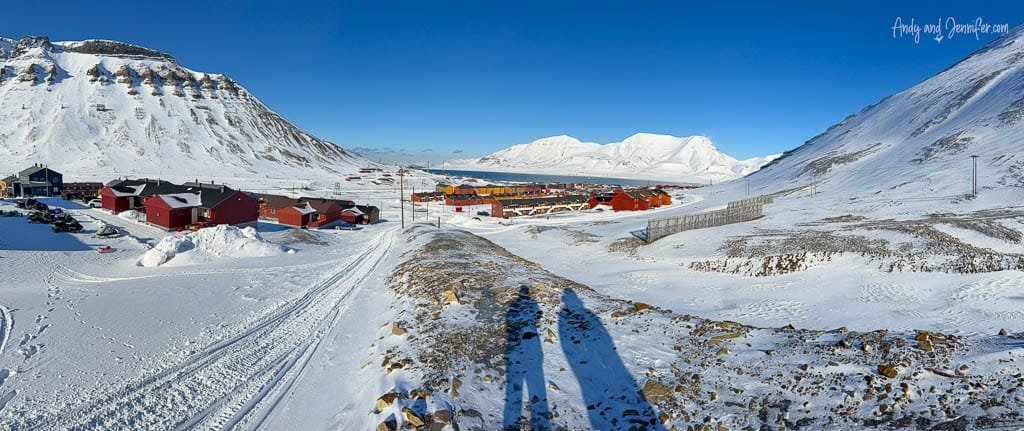 Snowy mountain village in Svalbard with red buildings and blue sky