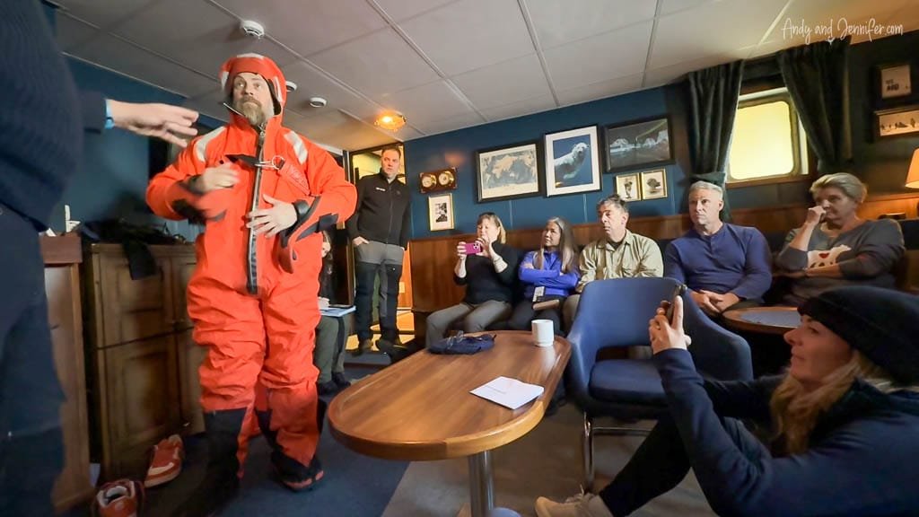 Crew member demonstrating survival suit to passengers
